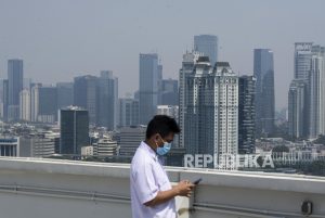 Petugas beraktivitas dengan latar belakang gedung-gedung bertingkat yang diselimuti polusi di Jakarta, Selasa (28/7). Polusi udara kembali menyelimuti langit Jakarta, sejak masa Pembatasan Sosial Berskala Besar (PSBB) memasuki masa transisi. Berdasarkan data AirVisual, kualitas udara Jakarta pada Selasa (28/7) mencapai angka 156 US AQI, yang tergolong tidak sehat.